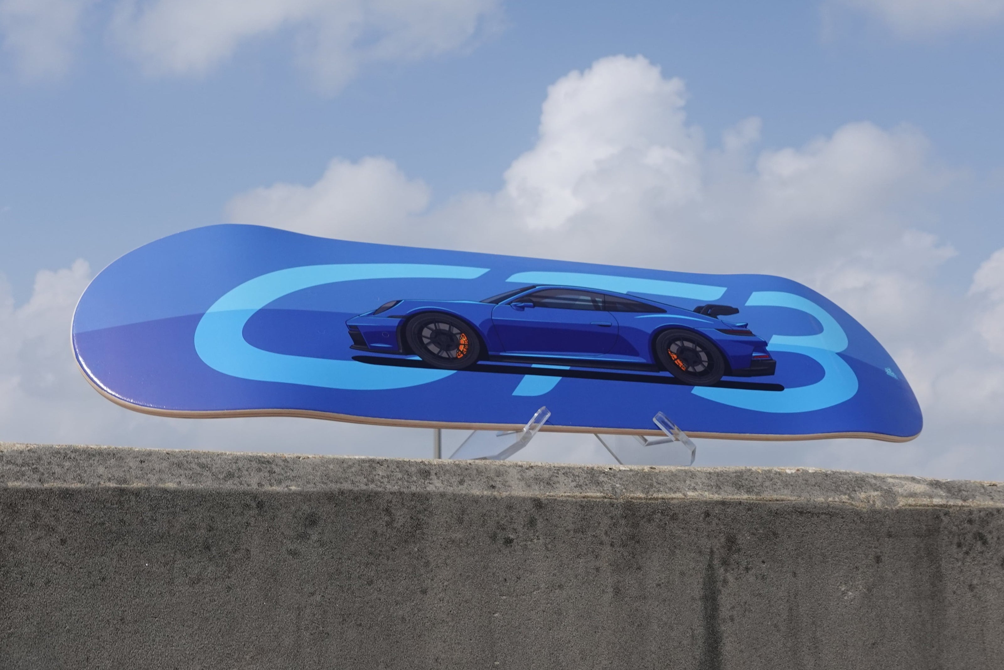 blue skateboard deck on a stand with sky in the background