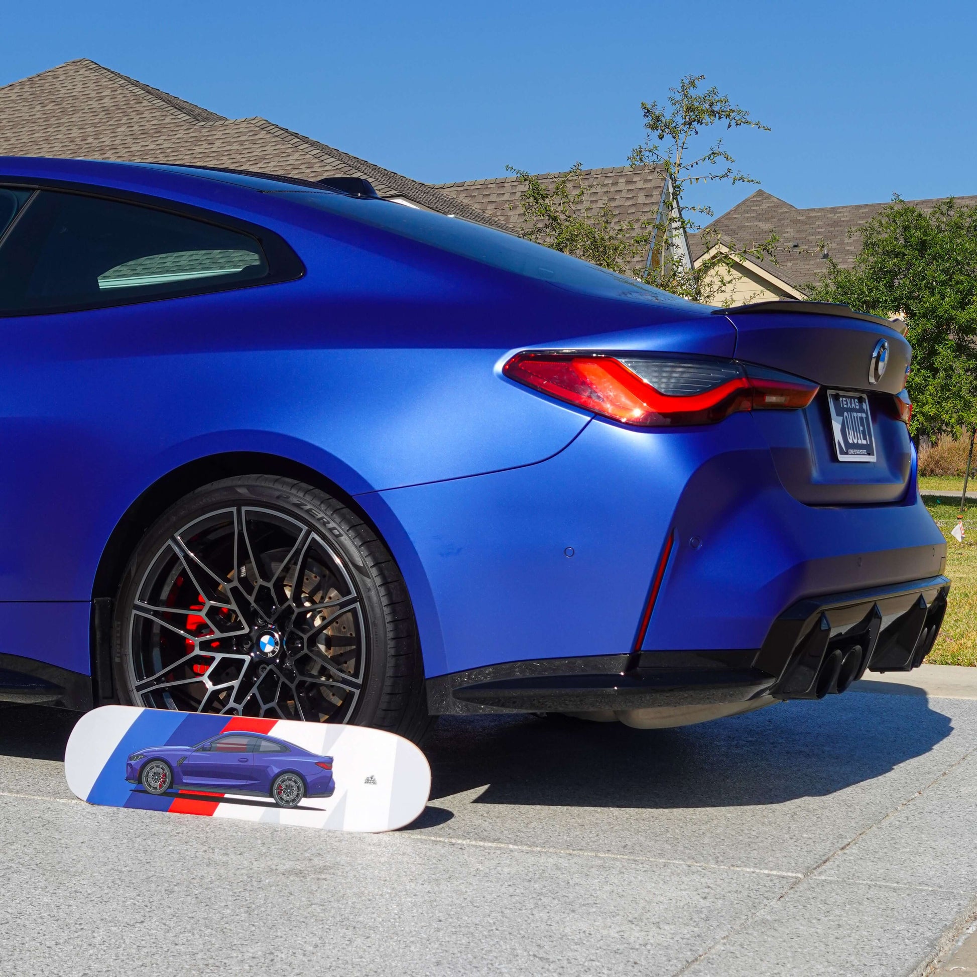 Blue car with a skateboard featuring a car design on a residential street.