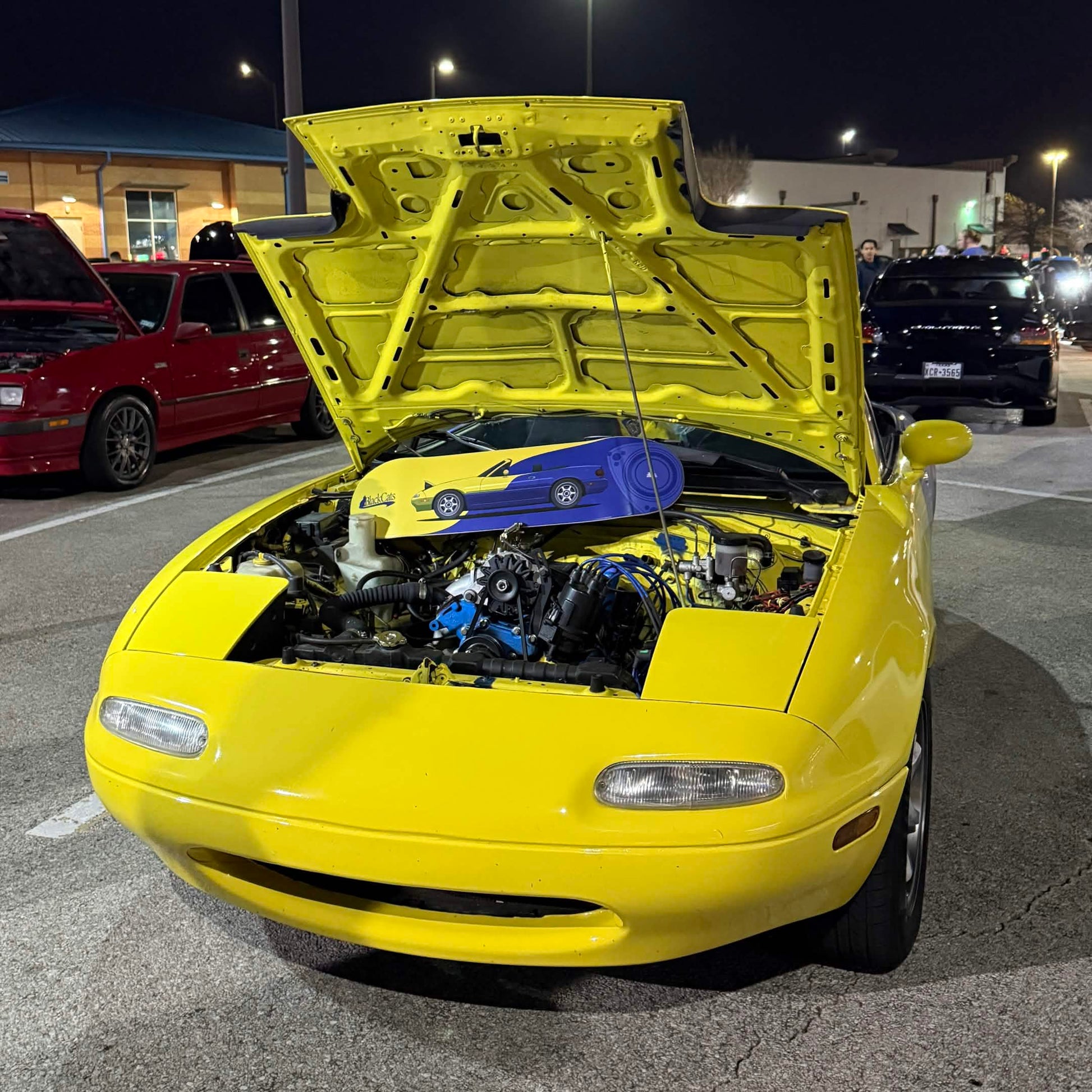 Yellow car with open hood in a parking lot at night
