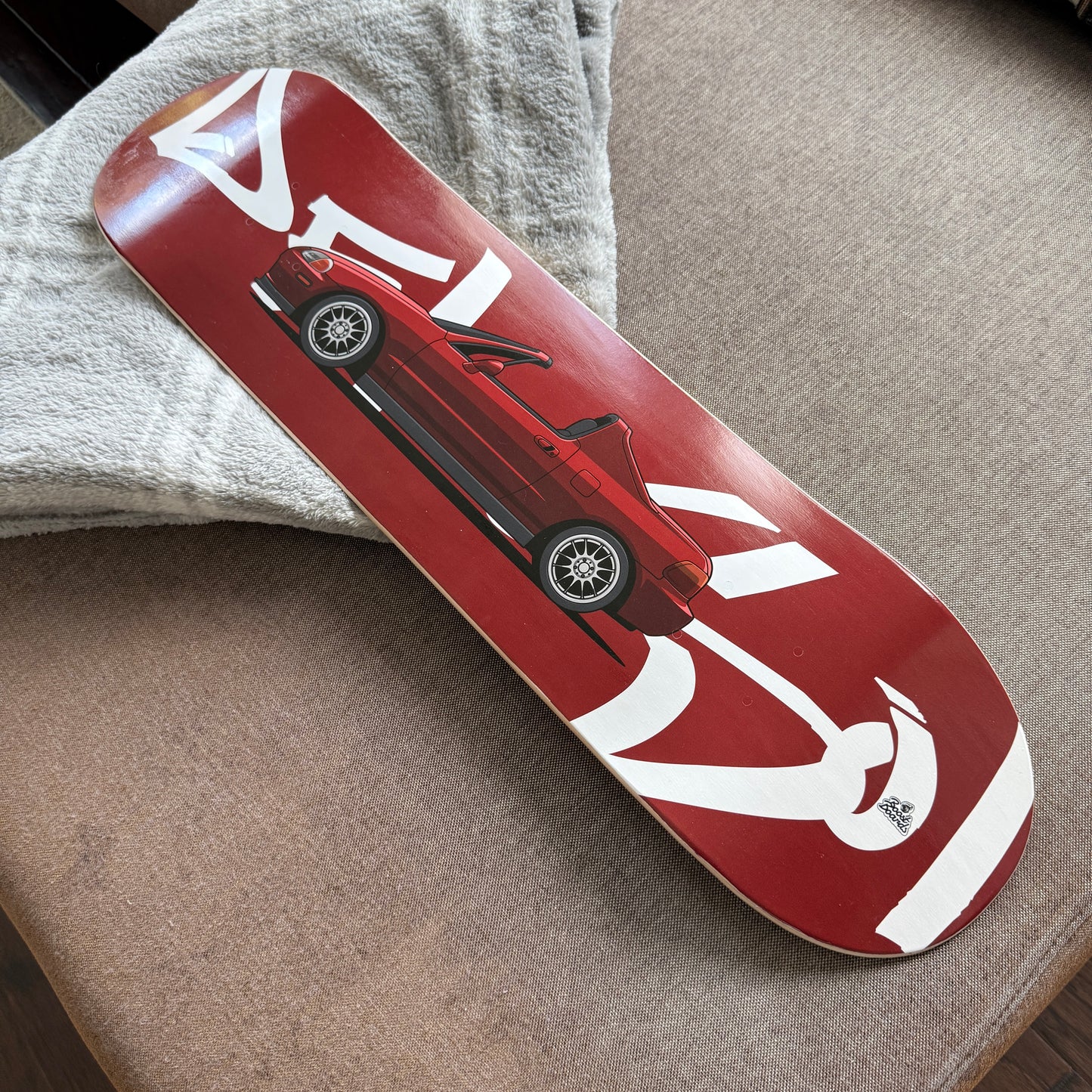 Red skateboard deck with white graphics on a gray surface